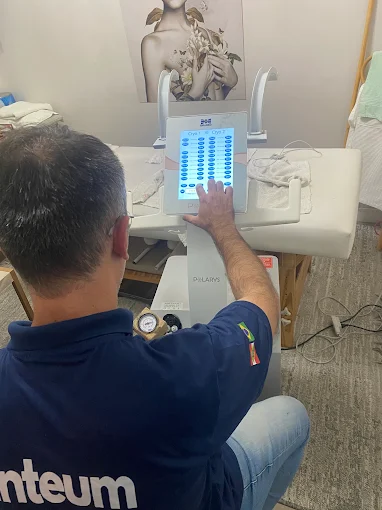 Técnico da Vinteum operando o painel de um equipamento estético em clínica